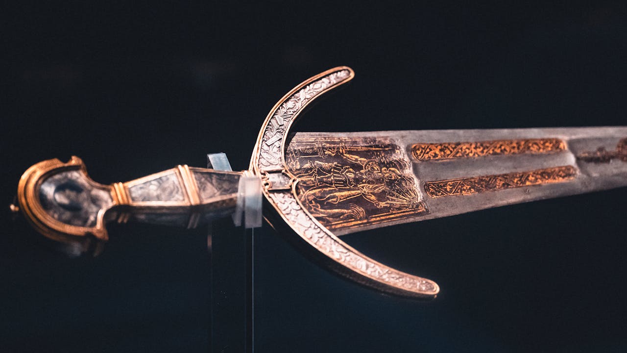 Close-up of an intricately designed historical sword with ornate details on blade and hilt.