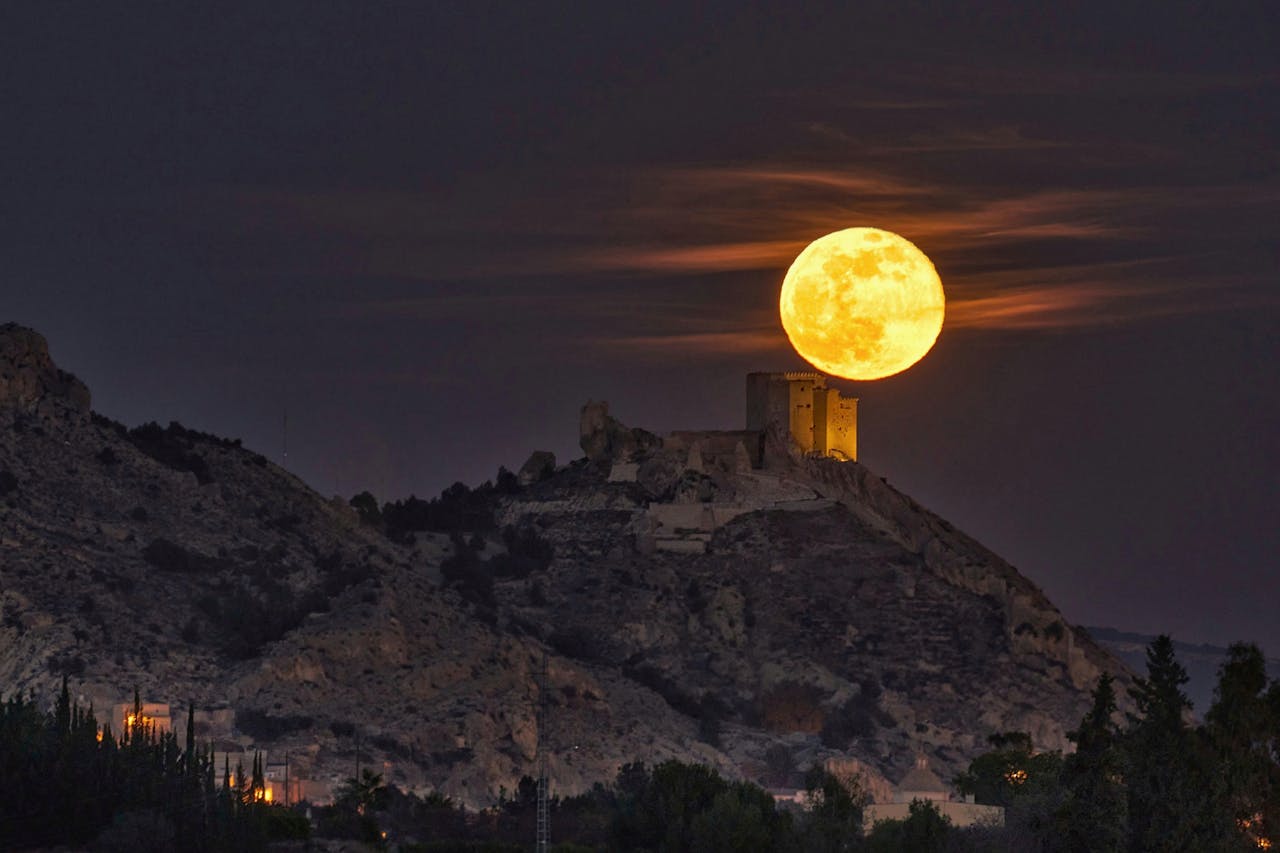 Majestic full moon rising over the historic Mula Castle in Murcia, Spain, showcasing serene night landscape.