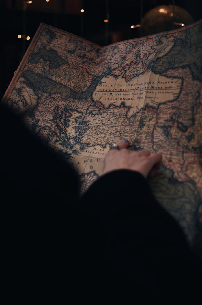 A person examining a detailed vintage map in a dimly lit environment, evoking curiosity and adventure.