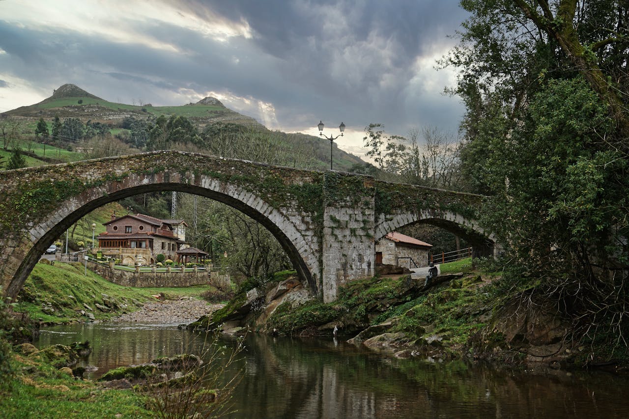 Scenic view of a stone arch bridge with mountains and river in Lierganes, Spain.