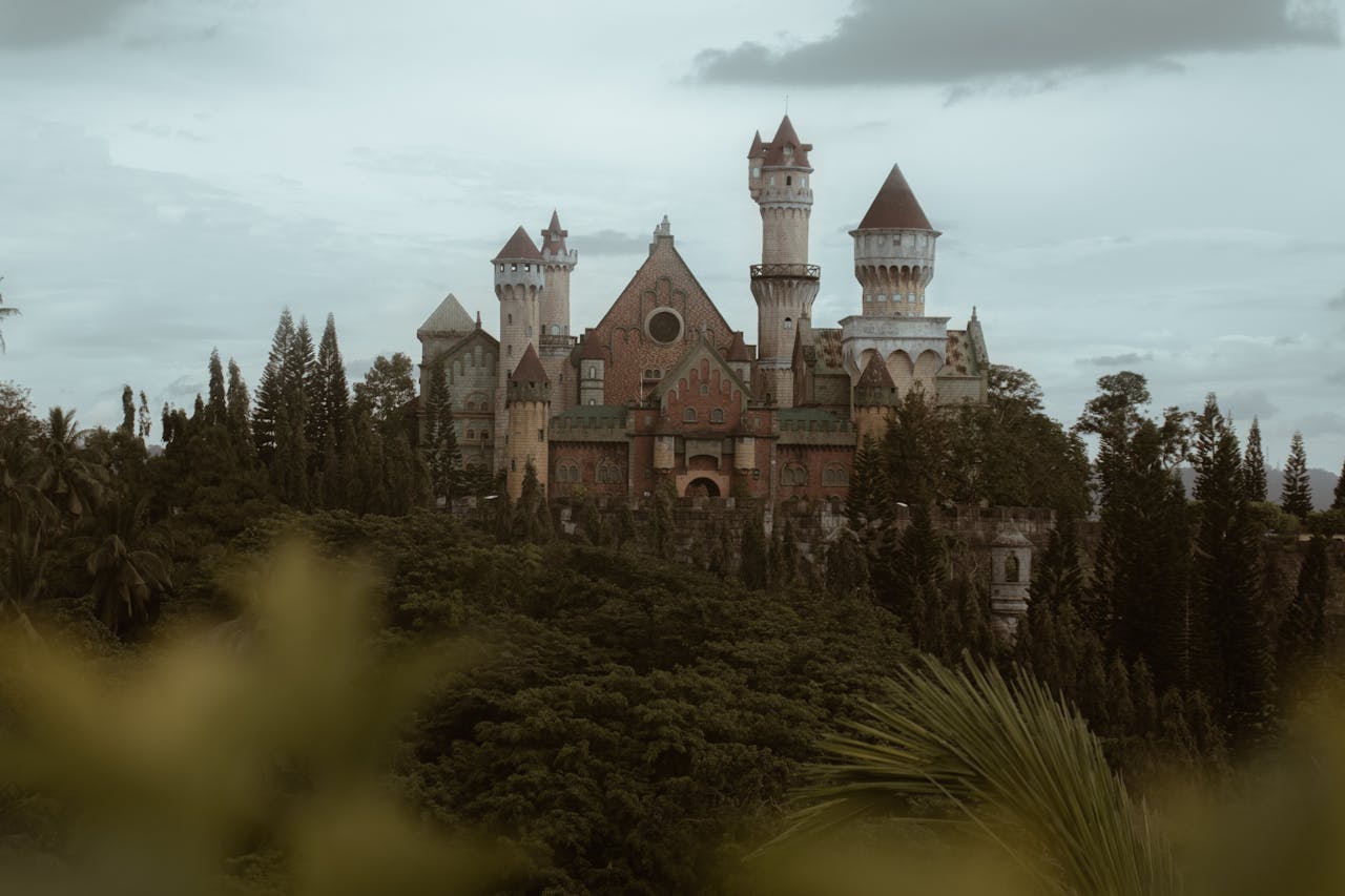 Fairytale-inspired castle nestled in Batangas, surrounded by verdant trees under a cloudy sky.